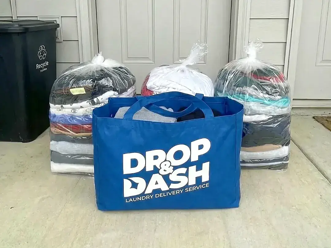 Three wrapped stacks of clean, folded laundry and a Drop & Dash bag delivered to a front door