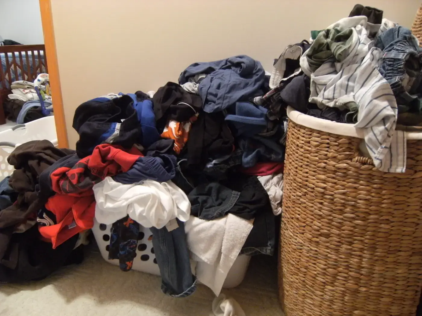A big pile of dirty laundry overflowing two hampers at home
