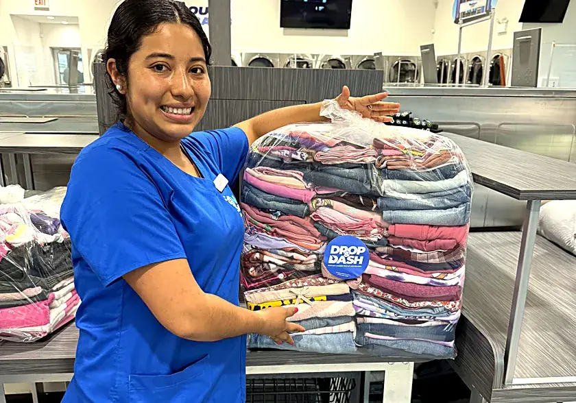 A Drop & Dash team member presenting a large wrapped bundle of clean folded laundry