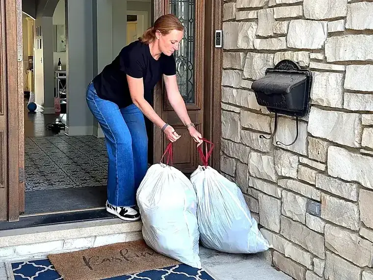 A customer setting two bags of laundry outside her front door