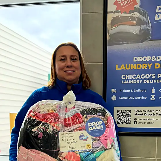 A team member with a wrapped order in front of a Drop & Dash poster